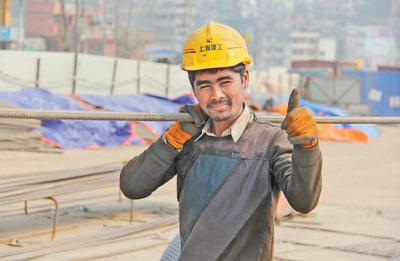 正在施工现场的尼泊尔建筑工人坦卡扛着钢筋,对记者竖起大拇指.